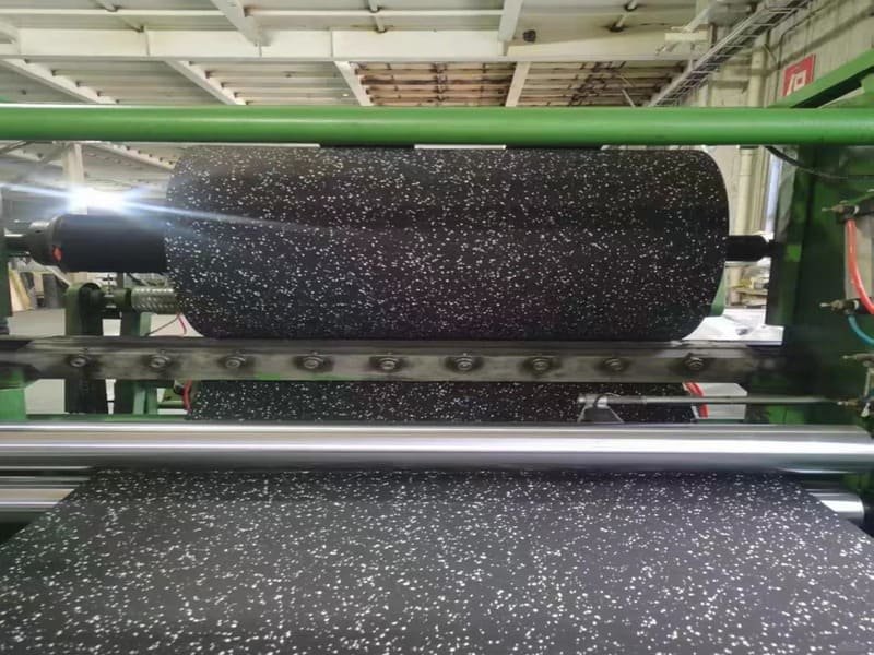 Worker installing underlayment with moisture barrier on concrete